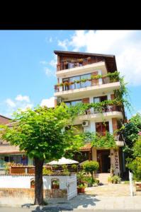 a tall building with a tree in front of it at Nirvana Guest House in Nesebar