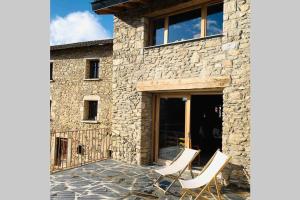 uma casa de pedra com duas cadeiras brancas num pátio em Charmante Maison de village: Prestation de Qualité, Tout confort, Terrasse em Targassonne