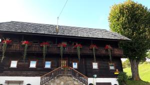 uma casa de madeira com flores vermelhas na varanda em Pension Barzaunerhof em Fresach