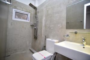 a bathroom with a white toilet and a sink at Lily Holiday Apartments in Hikkaduwa +49 photos