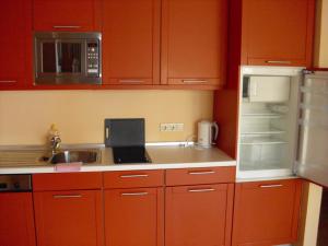 uma cozinha com armários vermelhos, um lavatório e um frigorífico em Fewoamglubigsee em Wendisch Rietz