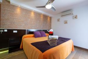 a bedroom with a bed with an orange bedspread and purple pillows at Hostal Casa Mercedes in Nerja