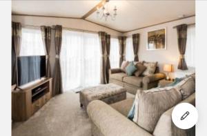 a living room with a couch and a television at Cairn View Chalet in Aviemore