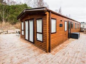 Holzhütte mit Fenstern auf einer Terrasse in der Unterkunft Cairn View Chalet in Aviemore