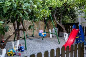 um parque infantil com baloiços e árvores num quintal em Oasis Apartments em Tolo
