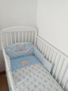 - un lit bébé blanc avec une couverture bleue dans l'établissement Casa da Rosarinha, à Água de Alto