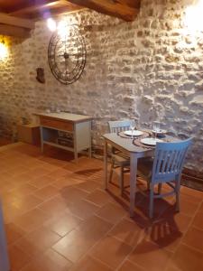 stół i krzesła w pokoju z kamienną ścianą w obiekcie gîte le tilleul de la Fontaine w mieście Alluy