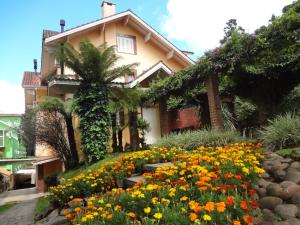 una casa con un jardín de flores delante de ella en Apartamento Aconchegante + Bikes, en Gramado