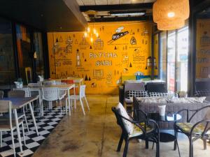 a restaurant with tables and chairs and a yellow wall at Baan Khun Nine in Ratchaburi