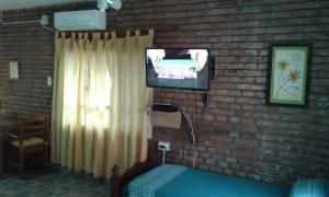 1 dormitorio con pared de ladrillo, TV y cama en Casa de Silvia, en Villa Carlos Paz 17 fotos más