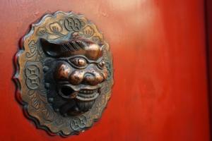 Ein Türknauf eines Dämons an einer roten Tür in der Unterkunft Beijing Yue Bin Ge Courtyard Hotel in Peking