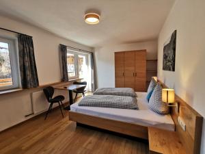 een slaapkamer met 2 bedden en een bureau bij Pension Haus in der Sonne in Fieberbrunn