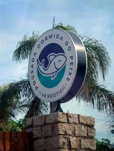 un panneau pour un club de dauphins au-dessus d'un mur de briques dans l'établissement Pousada Dormida do Peixe, à Praia do Rosa