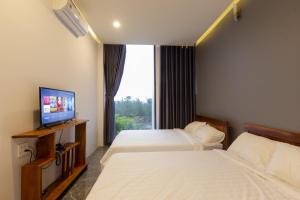 two beds in a room with a tv and a window at Ayaru Hotel in Tuy Hoa