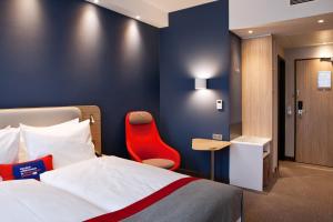 een hotelkamer met een bed en een rode stoel bij Holiday Inn Express - Darmstadt, an IHG Hotel in Darmstadt