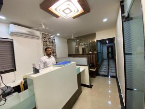 un homme debout à un comptoir dans un bureau dans l'établissement HOTEL DIVINE, à Mumbai