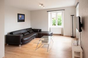 a living room with a black leather couch and a glass table at LE TOMIGITE in Dimbsthal