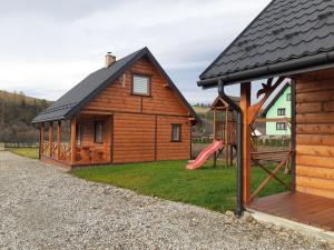 a log cabin with a slide and a playground at Sloneczny Domek in Kacwin