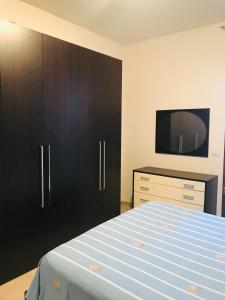 ein Schlafzimmer mit einem Bett, einer Kommode und einem TV in der Unterkunft Alghero Appartamento la Corbata in Alghero