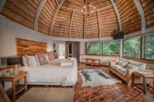 een slaapkamer met een bed, een bank en ramen bij Serenity Mountain and Forest Lodge in Malelane