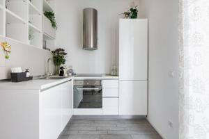 a white kitchen with white cabinets and a sink at Stupendo e accogliente apt (15 min dal Duomo) in Milan