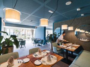 un restaurant avec des plafonds et des tables bleus et un homme debout au milieu dans l'établissement OCEANO Health Spa Hotel, à Punta del Hidalgo