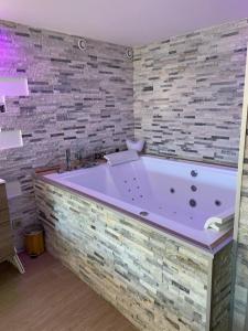 El baño incluye una gran bañera morada y una pared de piedra. en Le Menhir Jacuzzi Lit 200x200 en Le Cendre