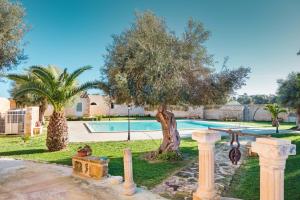 a villa with a swimming pool and a tree at Masseria Testaferrata in Syracuse