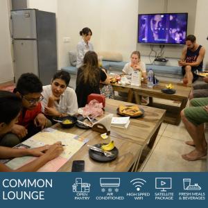 un grupo de personas sentadas alrededor de las mesas en una habitación en Blue Beds Hostel en Jaipur