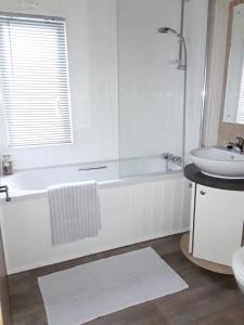 a white bathroom with a tub and a sink at Clearwater lodge Widemouth sands in Poundstock