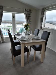 a dining room with a table with chairs and a window at Clearwater lodge Widemouth sands in Poundstock