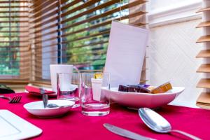 a table with a red table cloth with plates and glasses at St Marys Guest House in York