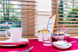 una mesa con un mantel rojo con utensilios. en St Marys Guest House, en York