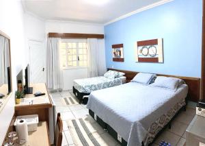 a bedroom with two beds and a desk and a television at Amarilis Flat Service in Riviera de São Lourenço