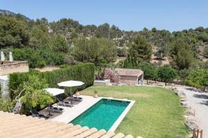 a swimming pool in a yard with chairs and umbrellas at Sa Tanca de sa Nina in Mancor del Valle