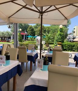 een restaurant met tafels en stoelen met een parasol bij Hotel Adriatico in Bibione