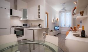 uma cozinha com armários brancos e uma mesa de vidro em Novella White em Florença