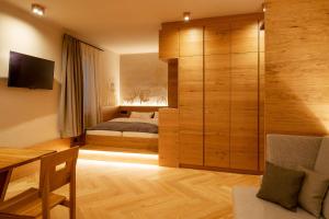 - une chambre avec un lit, un bureau et une télévision dans l'établissement Ladurner Suites, à Merano