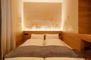 Ce lit se trouve dans un dortoir orné d'une peinture murale. dans l'établissement Ladurner Suites, à Merano