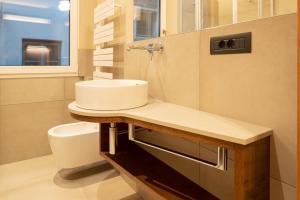 Un baño con lavabo, inodoro y ventana. en Ladurner Suites, en Merano 15 fotos más