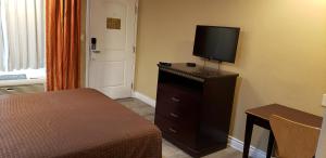 a hotel room with a bed and a television on a dresser at Santa Fe Inn Los Angeles in Huntington Park