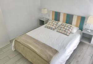 1 dormitorio con 1 cama blanca y 2 almohadas en Caleta Soul Apartment, en Puerto de Santiago