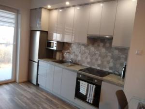 una cocina con armarios blancos y electrodomésticos de acero inoxidable en apartament, en Rzeszów