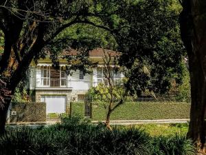 une maison blanche avec une clôture et des arbres dans l'établissement Casa Piabanha - Centro Histórico, à Petrópolis