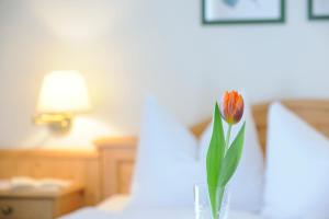 a flower in a vase on a table in a bedroom at Frühstückspension Huber in Fuschl am See