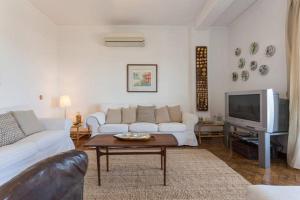 a living room with a white couch and a tv at Apartamento Vintage Frente ao Mar in Monte Gordo