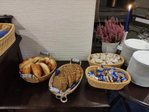 three baskets of bread on a table with plates at Hotel Am Kamp in Hannover