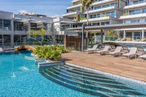 a swimming pool with chairs next to a building at Carmencita Studio B14 with pool & gym in Limassol