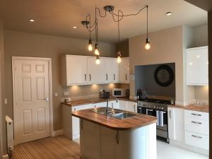 a kitchen with white cabinets and a wooden counter top at Cosy house set in historic town of Clitheroe in Clitheroe