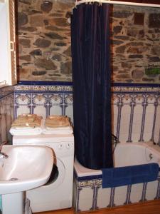 y baño con lavabo, bañera y lavadora. en Casa Trallera, en Colinas del Campo de Martín Moro